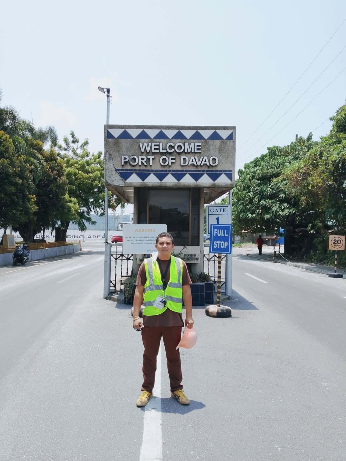 Roland Olano in a safety vest at the Port of Davao entrance gate, holding a hard hat